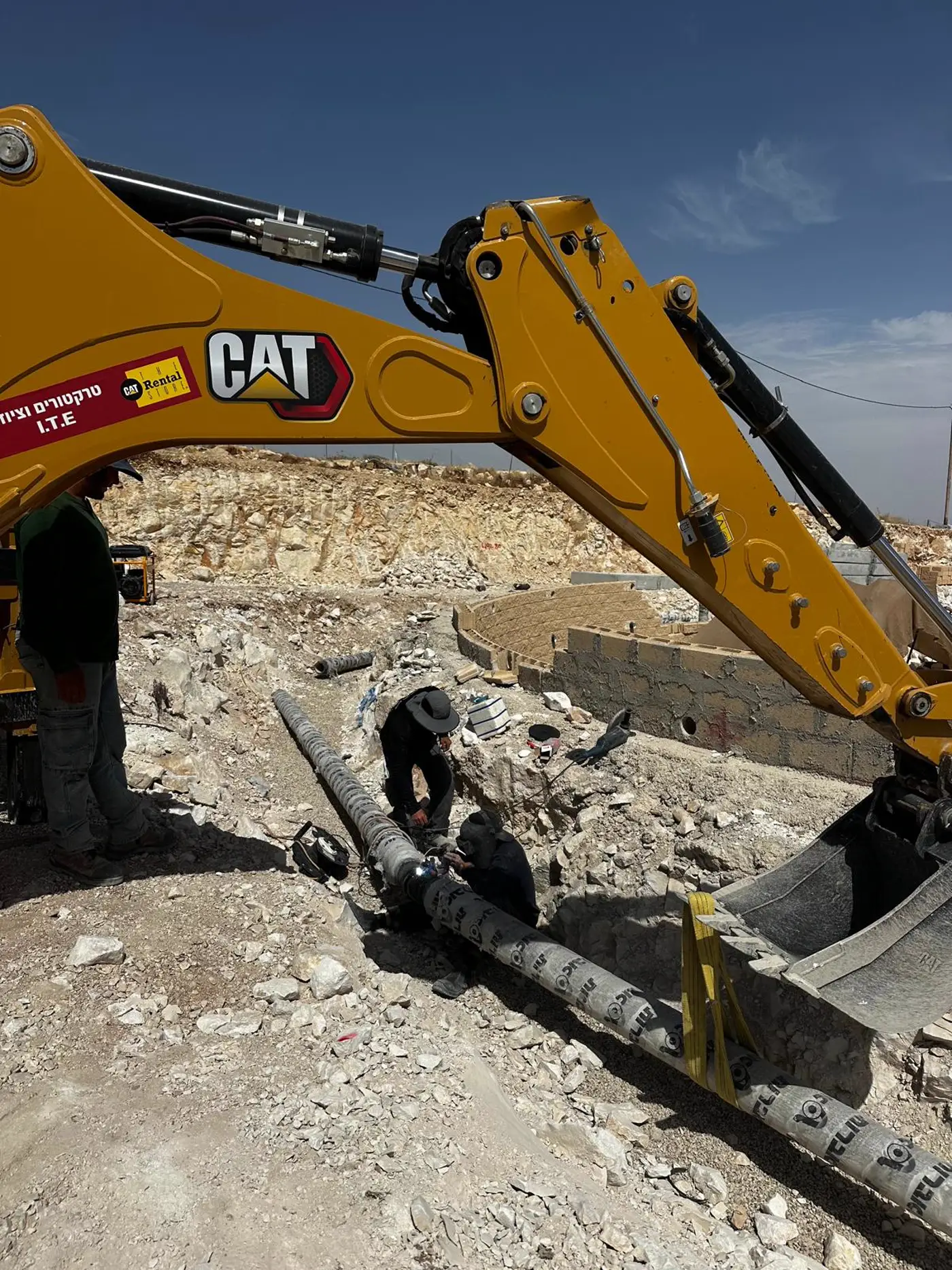 מחפר CAT מניח צינור בתעלה באתר של גוב מערכות
